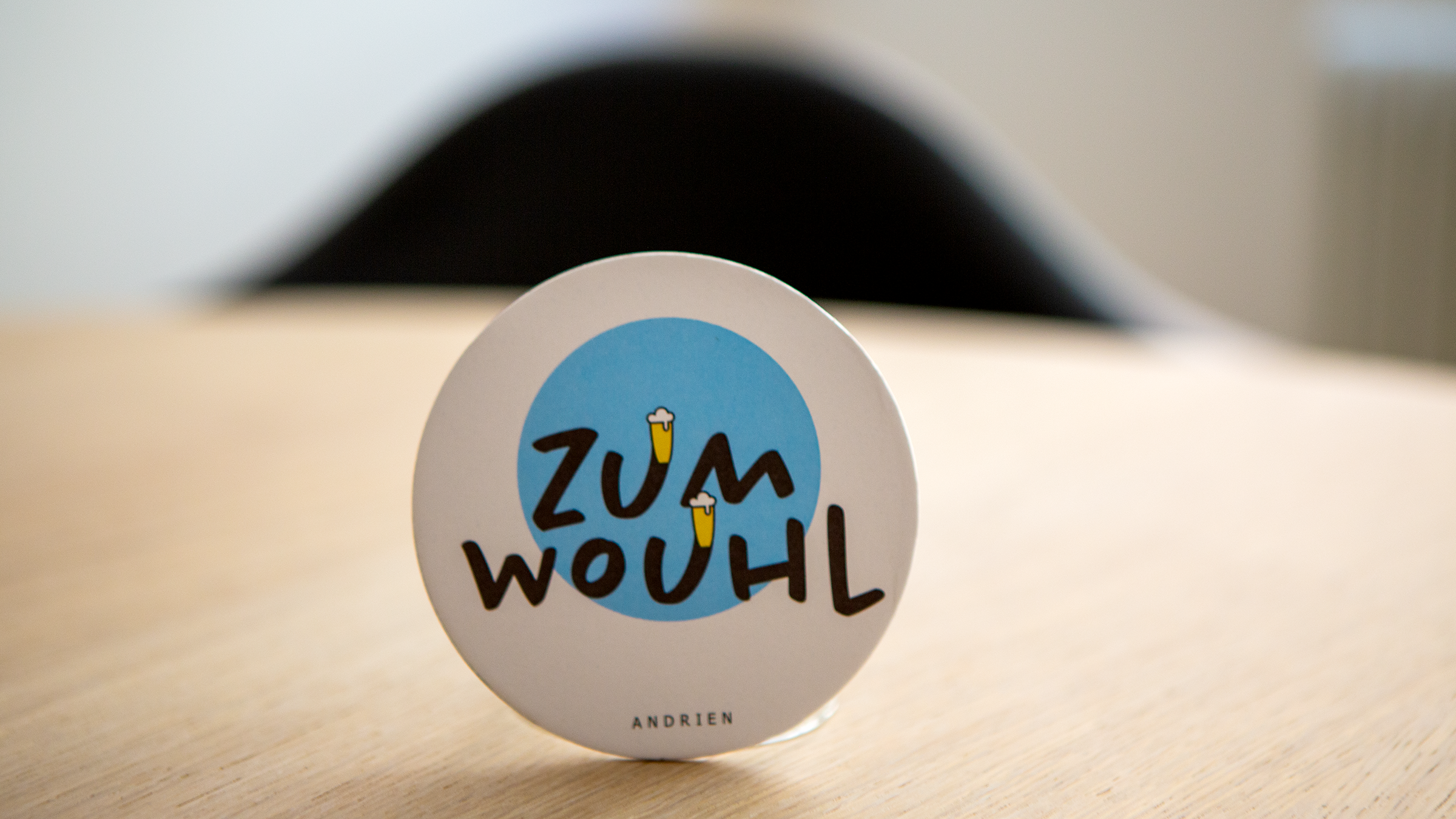 Bierdeckel des Hofschanks Andrien mit Südtiroler Trinkspruch, hellblauem Farbelement und Bierglas-Illustrationen.