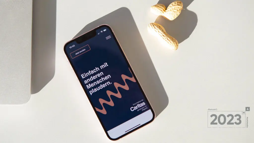 Ein Smartphone zeigt die Startseite von Plaudernetz. Darunter befindet sich das Auszeichnungslogo des Annual Multimedia Awards in Silber 2023.
